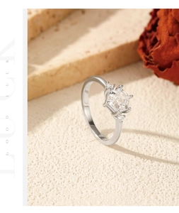Macro detail of silver hexagonal diamond ring with emerald cut stones on stone surface