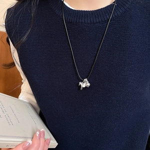 Détail du pendentif cheval argenté avec perle grise sur un mannequin en pull