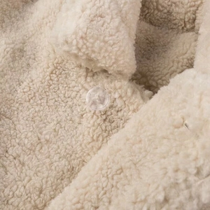 Dettaglio della giacca sherpa crema con trama morbida e bottone in resina