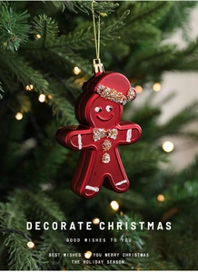 Close-up of burgundy gingerbread man ornament with beads hanging on a Christmas tree