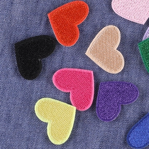 Colorful heart embroidered patches in red pink and blue on denim background for DIY clothing