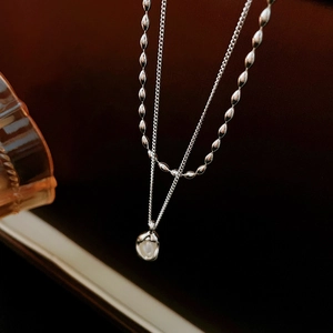 Detail view of silver layered necklace featuring oval beads and liquid metal pearl pendant