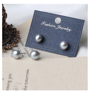 Macro detail of metallic grey pearl earrings with silver posts on elegant art paper