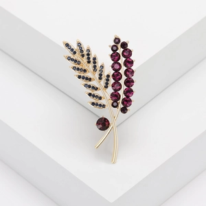 Elegant gold wheat brooch with purple round crystals and blue marquise stones on white base