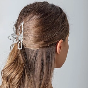 Détail d'une grande pince à cheveux papillon en métal argenté au design ajouré