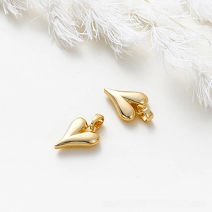 Detailed macro of two polished 18K gold heart charms with smooth reflective surface