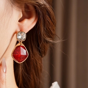 Gros plan de boucles d'oreilles vintage dorées avec cristaux rouges et clairs sur mannequin