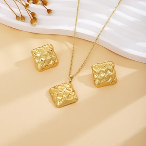 Detail showing golden rhombic woven texture necklace and matching stud earrings on display