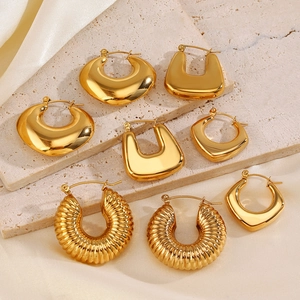 Macro detail of assorted gold geometric hollow earrings on textured stone display