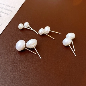 Set of four pairs of freshwater pearl studs in varying sizes on dark leather background