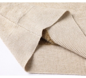 Dettaglio della fodera in pile spesso e bordo a coste del maglione in maglia color avena