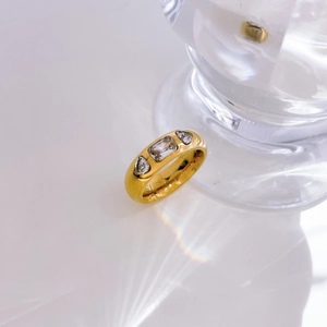 Detailed view of wide gold band ring featuring three inset rectangle and oval zircon stones