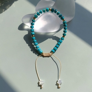 Detail of turquoise beaded bracelet with golden accents and star-shaped shell charms