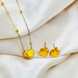 Close-up of a gold heart jewelry set including a pendant necklace and stud earrings