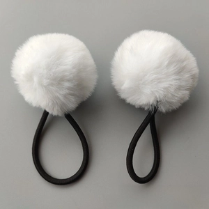 Close-up of white faux fur pom pom hair ties with elastic black rubber bands