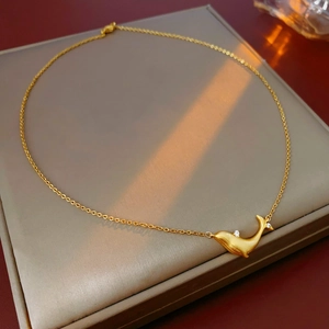 Close-up of golden whale pendant with zircon stones on a refined gold chain link