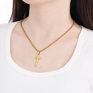 Detailed view of model wearing a gold polished cross pendant necklace with box chain
