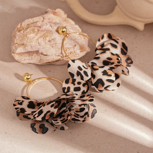 Retro gold leopard print fabric petal hoop earrings on a stone texture background
