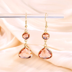 Detailed macro view of gold waterdrop earrings with amber crystals on silk background