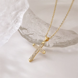Detail of gold cross pendant with micro-pave turquoise and zircon stones on a fine chain