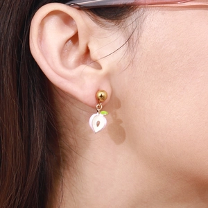 Close-up of sweet pink enamel peach charm earrings with golden studs on female ear