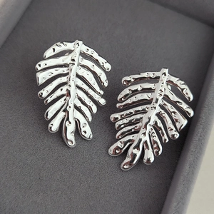 Silver palm leaf earrings with hammered texture finish in a purple velvet jewelry box