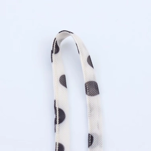 Close-up of black polka dot print on white fabric with detailed knit texture and straps