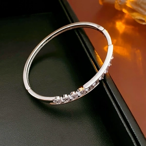 Détail d'un bracelet jonc argenté avec zircons sertis griffes sur un plateau à bijoux