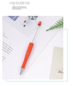 Detail of an orange retractable pointer pen with silver metal accents on a magazine page