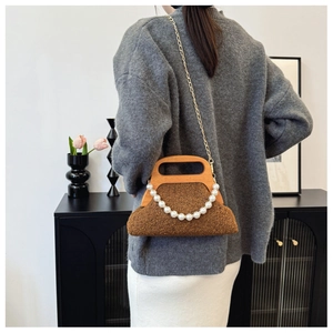 Brown plush handbag with wooden handle and pearl chain detail worn by a model