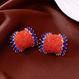 Macro detail of vintage C-shaped earrings with red and blue pavé crystals on satin