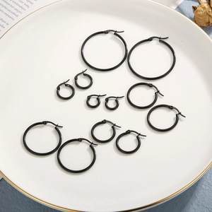 Black stainless steel hoop earrings in multiple sizes displayed on a ceramic plate