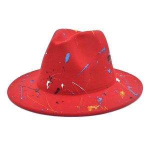 Détail d'un chapeau fedora en laine rouge orné de graffitis artistiques et éclats de peinture