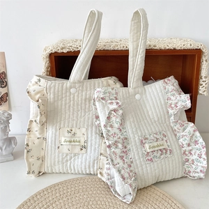 Detailed view of quilted cotton wrist bags with floral ruffles and branded fabric label