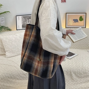 Detail of wool plaid tote bag with metal plaque showing thick autumn fabric texture