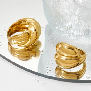 Polished gold geometric twist rings for women on a reflective mirror water surface
