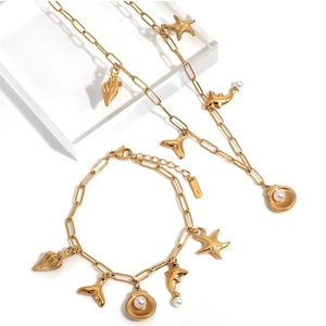 Golden ocean jewelry set with starfish, shell and dolphin charms on a display stand