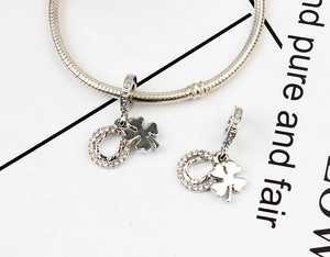 Macro detail of silver horseshoe and four-leaf clover charms set with clear zircons