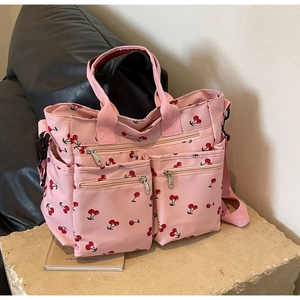 Close-up of pink cherry print tote bag with multiple zipper pockets and shoulder strap