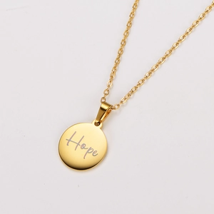 Close-up of golden round pendant with Hope engraving on a stainless steel chain