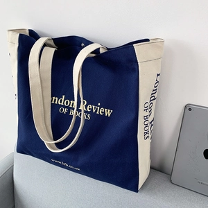 Dettaglio della borsa in tela blu navy su un divano con iPad per le dimensioni