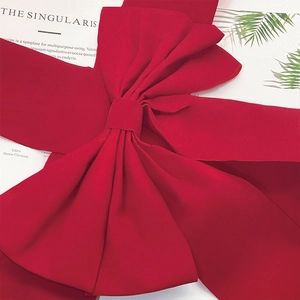Close-up of a large red velvet Christmas ribbon bow on a decorative magazine background