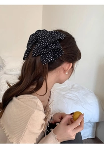 Detailed back view of a black polka dot fabric bow hair clip worn on a bun hairstyle