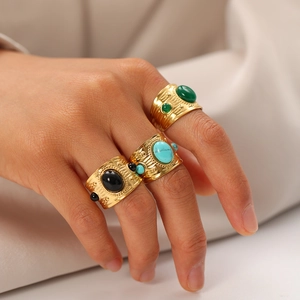 Detail of vintage gold-plated titanium steel rings with turquoise and onyx inlay on silk