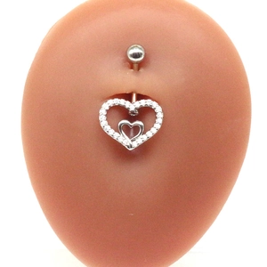 Macro shot of silver heart belly button ring with zircon stones on skin-toned model