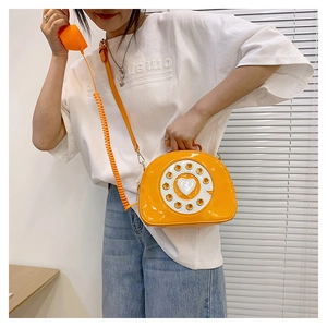 Macro detail of glossy patent leather orange phone bag with vintage dial and receiver