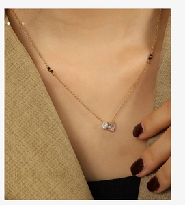 Close-up of double zircon pendant necklace with gold chain and black beads on a model