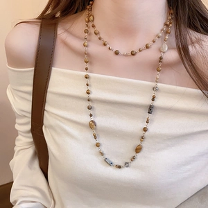 Macro shot of layered gold-plated necklace with vintage earth-tone geometric beads
