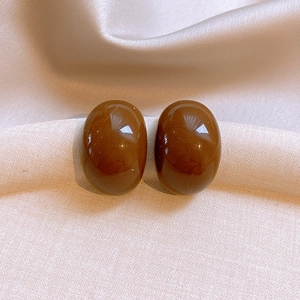 Detailed view of glossy amber oval resin stud earrings on elegant silk fabric