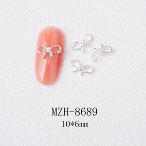 Macro detail of silver alloy bow nail charm with white pearl, 10x6mm size measurement